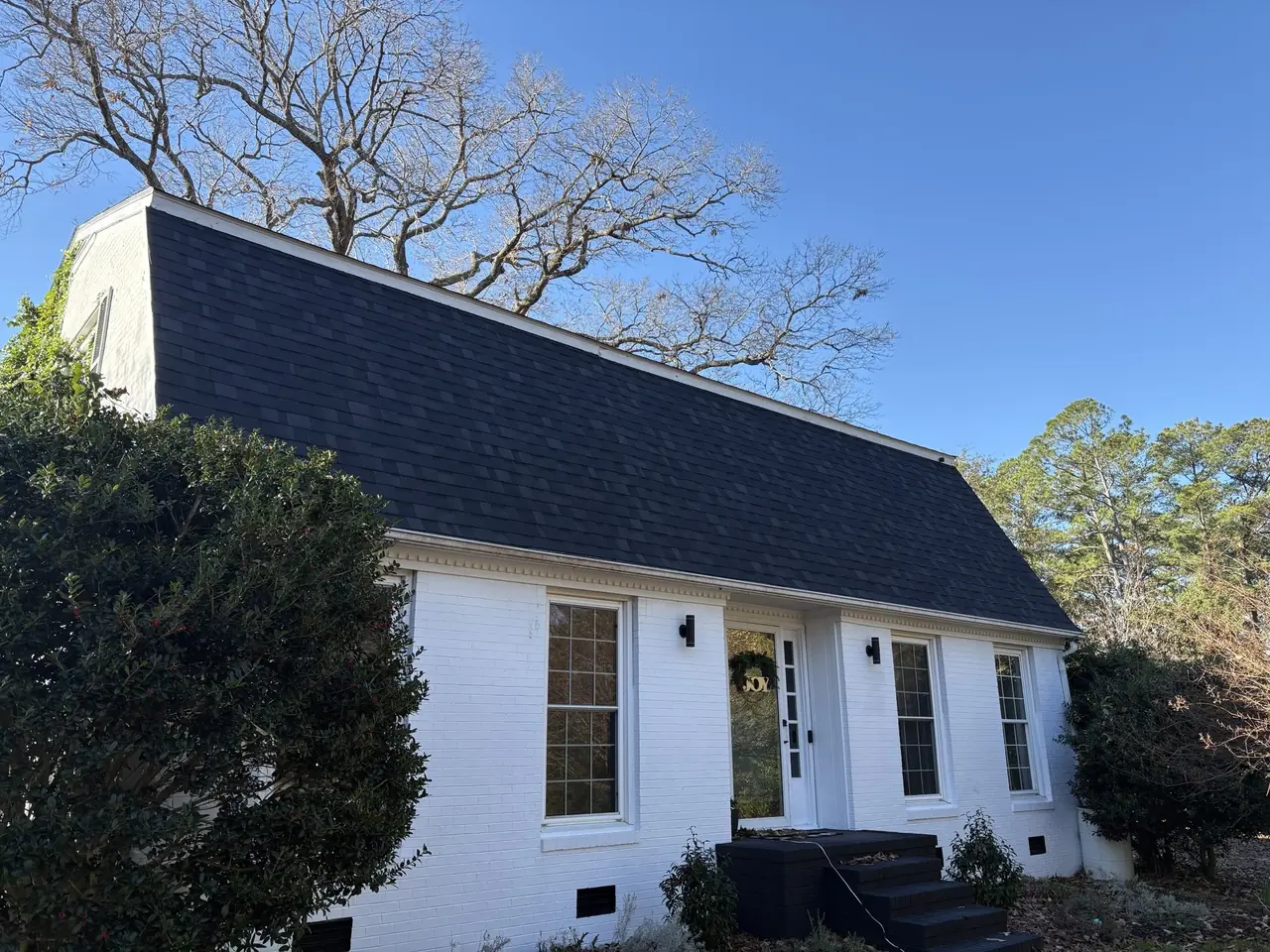 White painted-brick gambrel home in New Bern, NC with a new charcoal architectural shingle roof