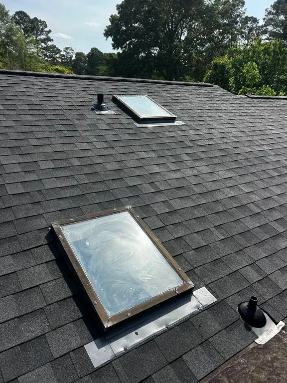 Two skylights set in new metal flashing in a new dark architectural shingle roof in New Bern, NC